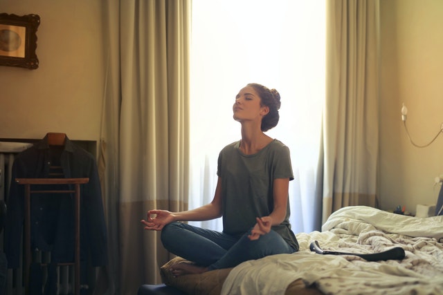 Woman meditating in bedroom.